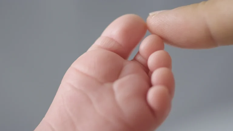 Mão segurando um bebê ao toque com foco nas pontas dos dedos, imagem que ilustra como a tecnologia pode tornar o resultado do teste do pezinho mais rápido.